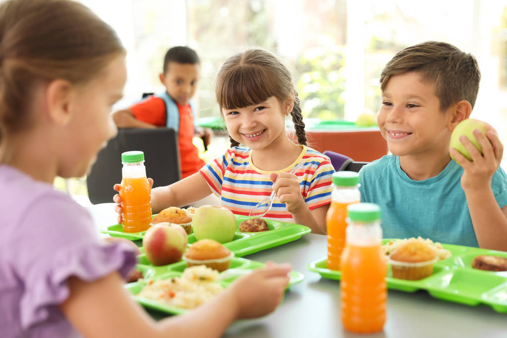 Kinderen zitten aan tafel en eten van gezonde voeding tijdens pauze op school - Foto, afbeelding