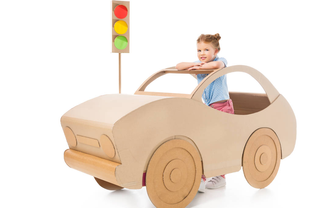 stylish adorable kid playing with cardboard car and traffic lights on white - Photo, Image