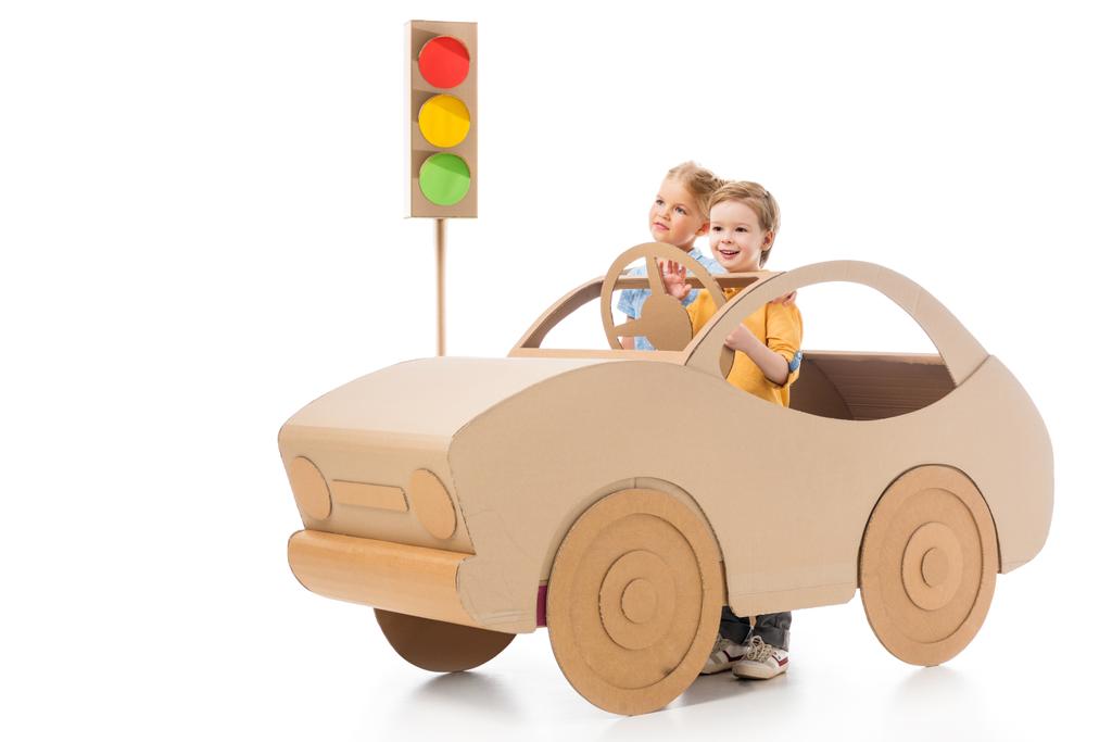 brother and sister playing with cardboard car and traffic lights, on white - Photo, Image