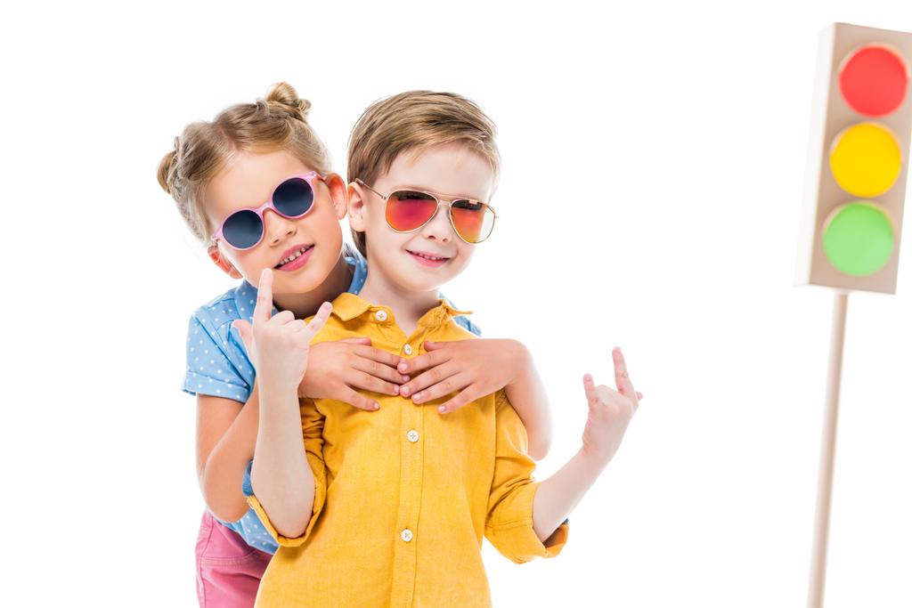 bambini alla moda in occhiali da sole, ragazzo che mostra segni rock n roll, isolato su bianco con semafori in cartone sullo sfondo
 - Foto, immagini