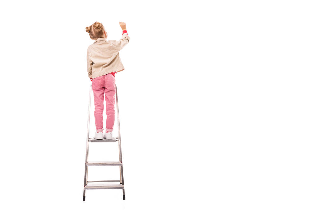Rückansicht von Schulkind, das auf Leiter steht und isoliert auf weiß schreibt - Foto, Bild