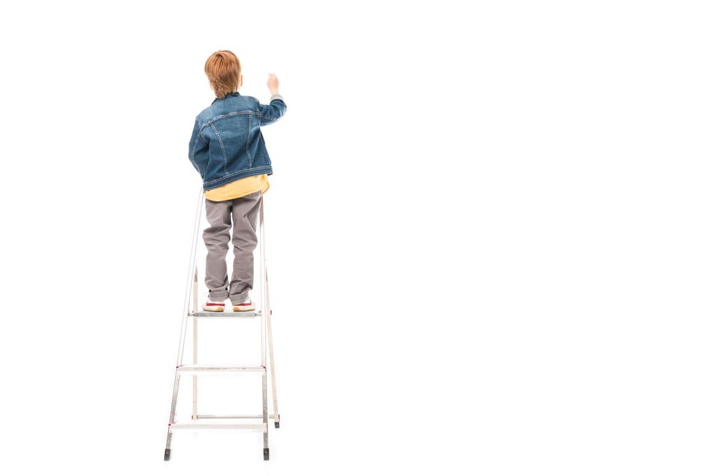 zadní pohled na školáka, stojící na žebříku a psaní izolované na bílém - Fotografie, Obrázek