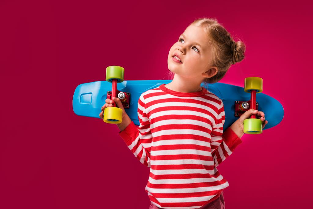 очаровательный стильный ребенок позирует с пенни доска изолированы на красный
 - Фото, изображение