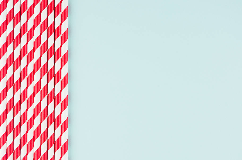 Смішний святковий яскравий абстрактний фон - смугасті червоні коктейльні соломинки на пастельному фоні з цукерками м'ятного кольору
. - Фото, зображення