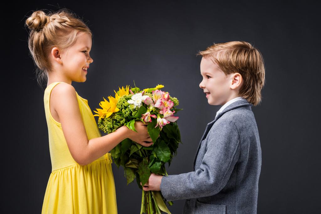 μικρό ζευγάρι χαμογελώντας με μπουκέτο λουλούδια, απομονώνονται σε γκρι - Φωτογραφία, εικόνα