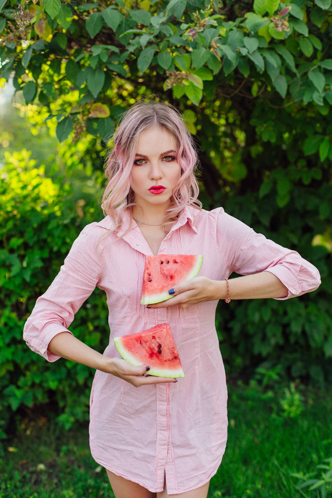 Beautiful young woman with pink hair holding two slices of sweet juicy watermelon - Photo, Image