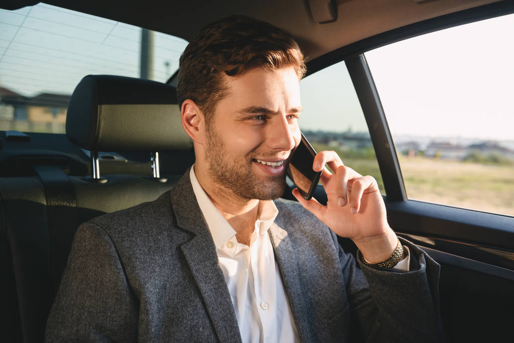 Портрет успішного режисера чоловіка в костюмі, який розмовляє на смартфоні, сидячи в машині бізнес-класу
 - Фото, зображення