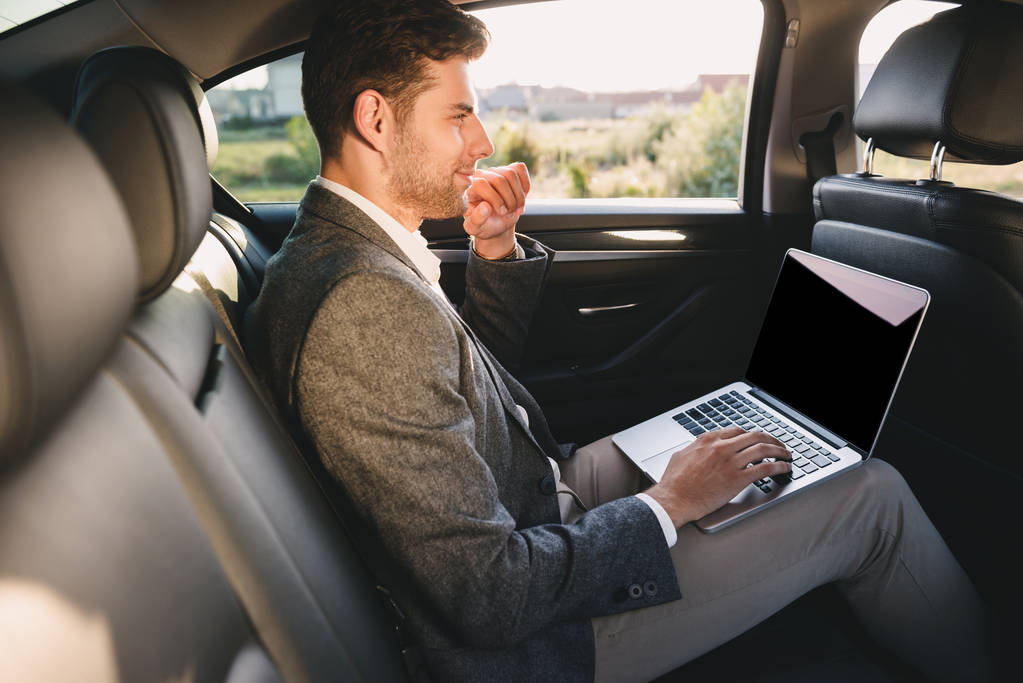 Retrato de homem bonito de terno trabalhando no laptop enquanto volta sentado no carro de classe executiva
 - Foto, Imagem