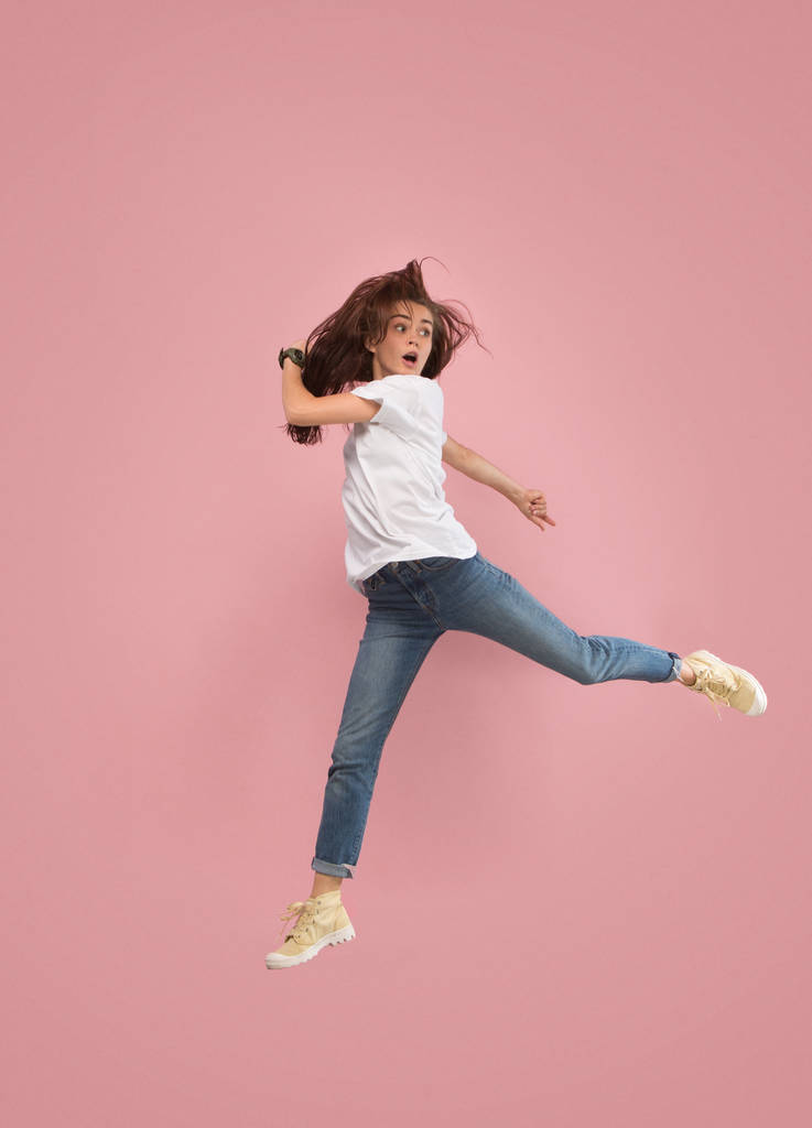 Libertad de movimiento. Mujer bastante joven saltando sobre fondo rosa
 - Foto, imagen