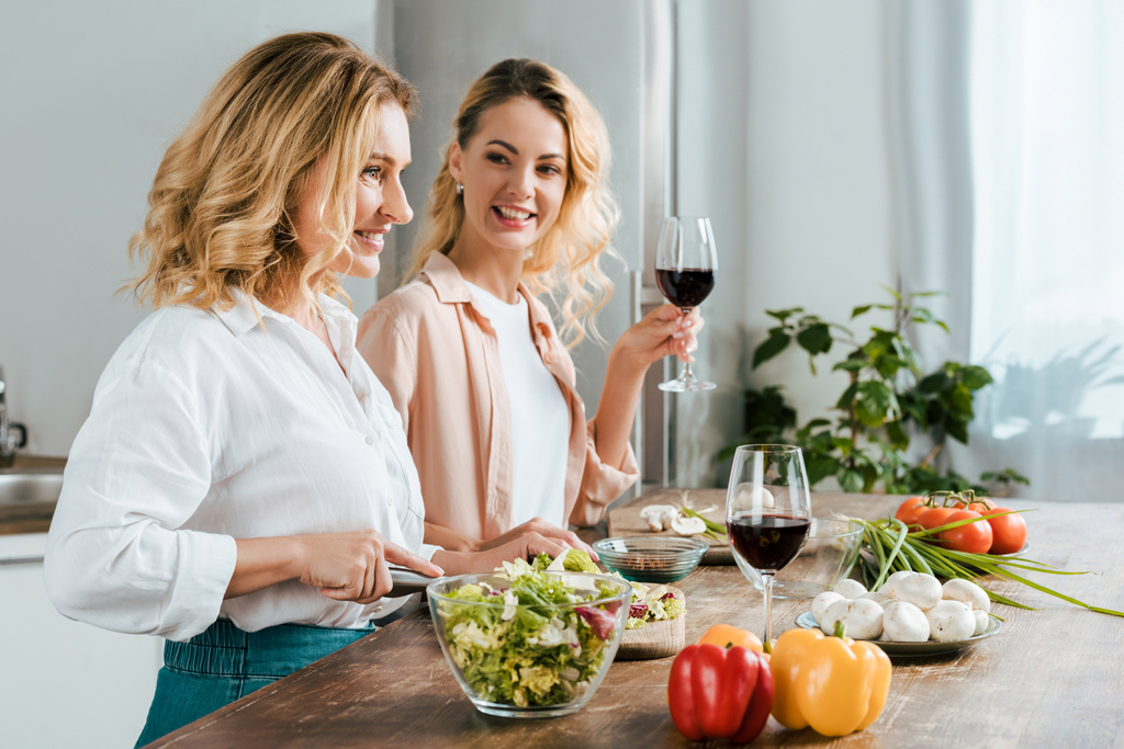 mère mature heureuse et fille adulte faisant salade ensemble à la cuisine
 - Photo, image