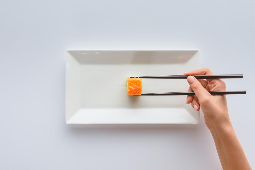 обрізаний знімок людини з паличками, що тримають смачні суші на білій тарілці ізольовані на білому
 - Фото, зображення