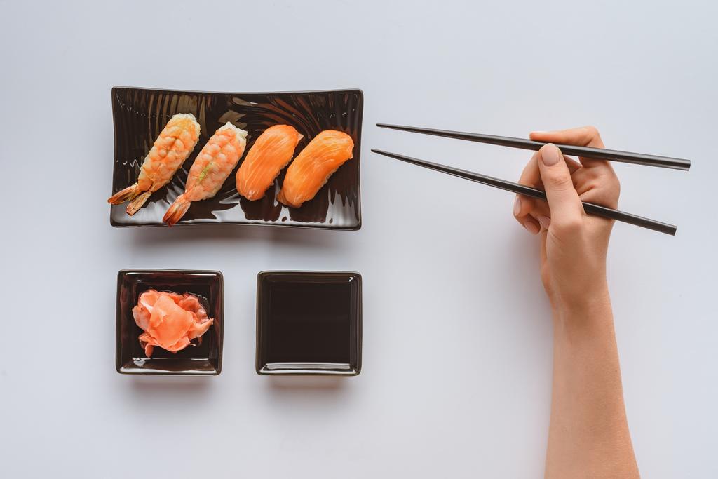 обрезанный снимок человека, держащего палочки и поедающего вкусные суши изолированные на белом
 - Фото, изображение