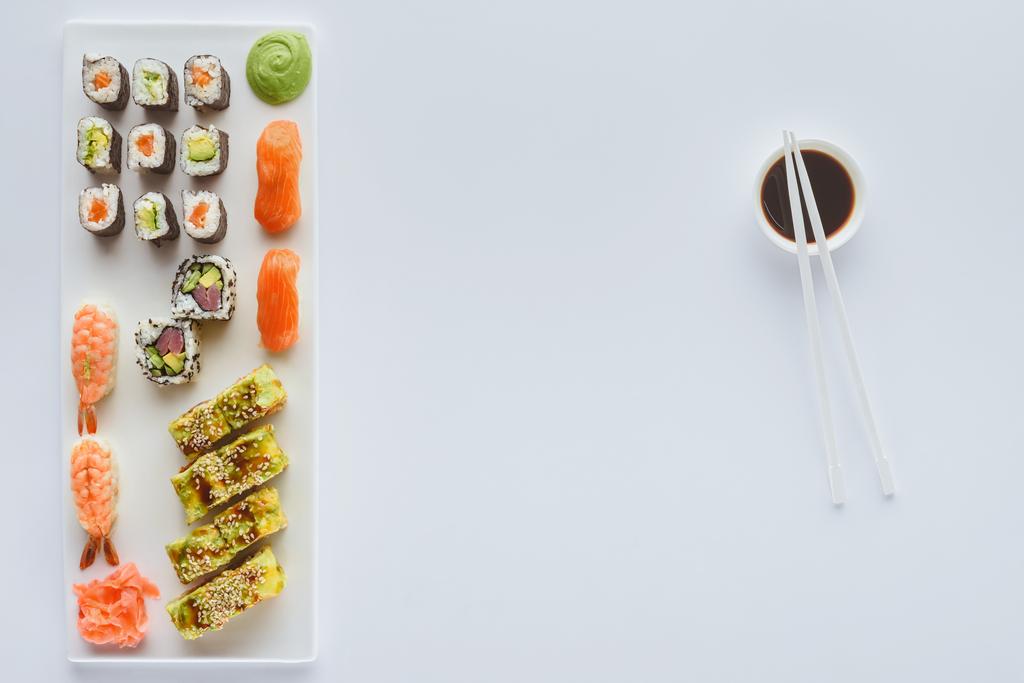 Gourmet-Sushi-Set und Sojasauce in Schüssel mit Essstäbchen isoliert auf weißem Hintergrund   - Foto, Bild