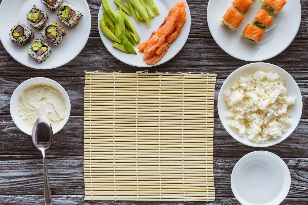 bovenaanzicht van ingrediënten voor het bereiden van heerlijke sushi op houten tafel - Foto, afbeelding