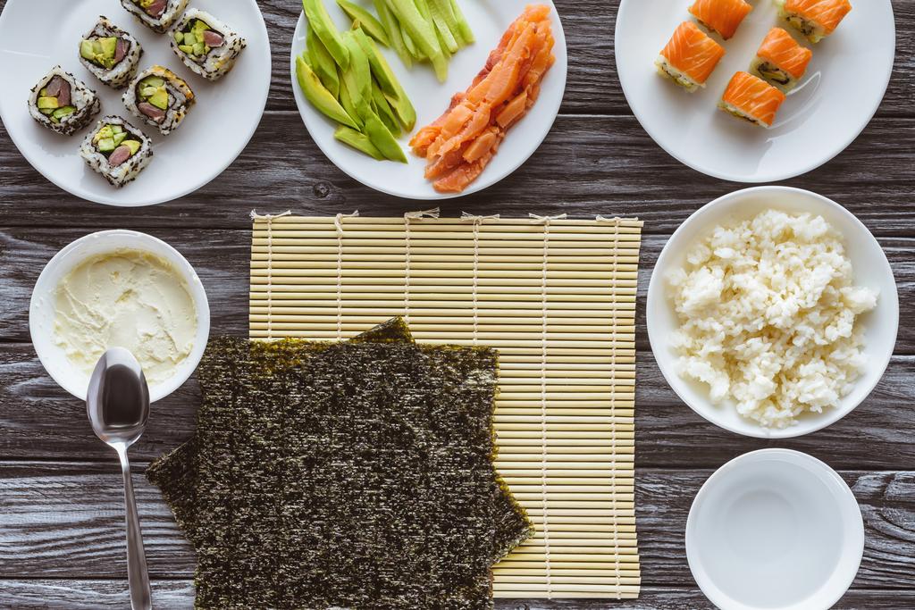 vue du dessus des feuilles de nori et des ingrédients pour préparer de délicieux sushis sur une table en bois
 - Photo, image