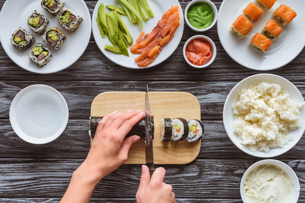 részleges felülnézet személy vágás finom sushi tekercs kés - Fotó, kép