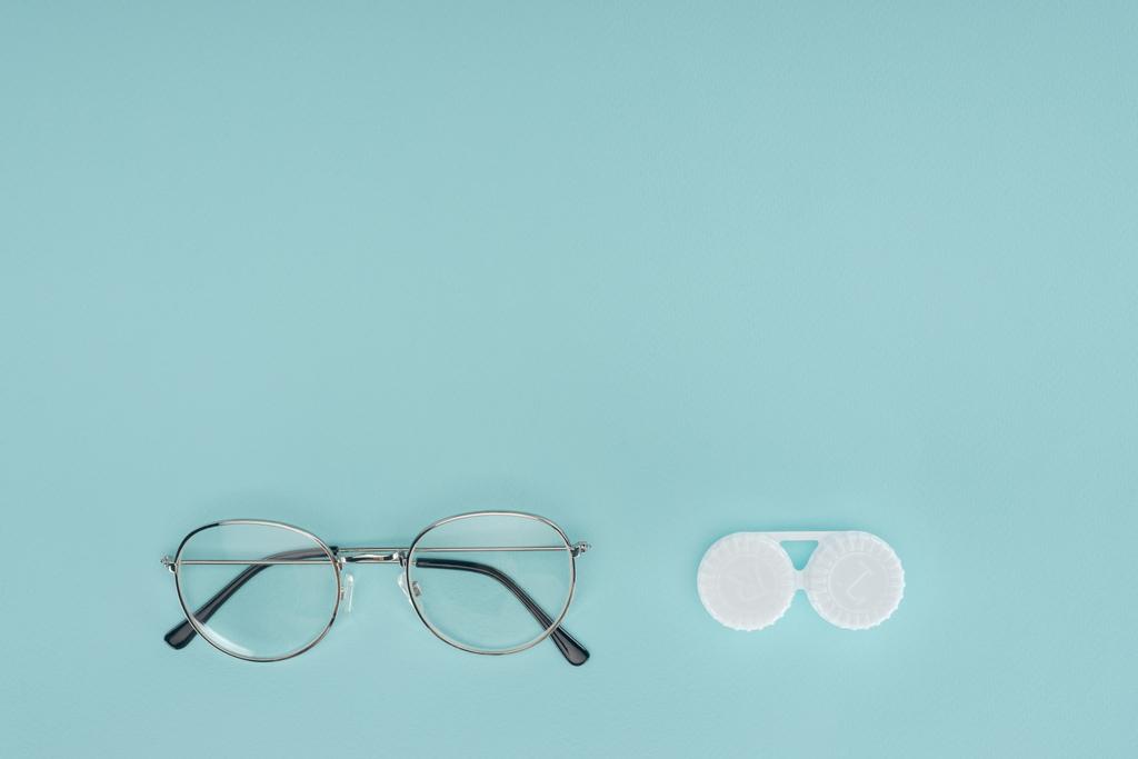 vista superior de óculos e lentes de contato recipiente no fundo azul
 - Foto, Imagem