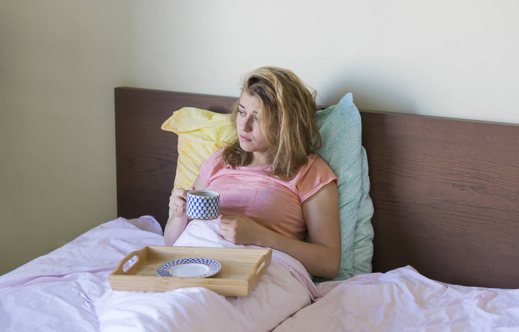 1 chica blanca en la cama debajo de una manta con una taza de café
 - Foto, imagen