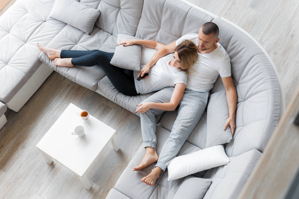 Jeune couple reposant sur un canapé à la maison. Style de vie de détente familiale
 - Photo, image