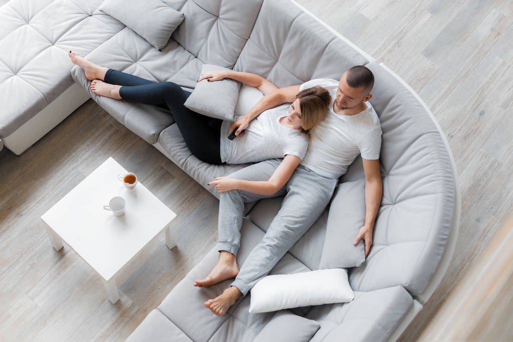 Young couple resting on sofa at home. Family relaxation lifestyle - Photo, Image