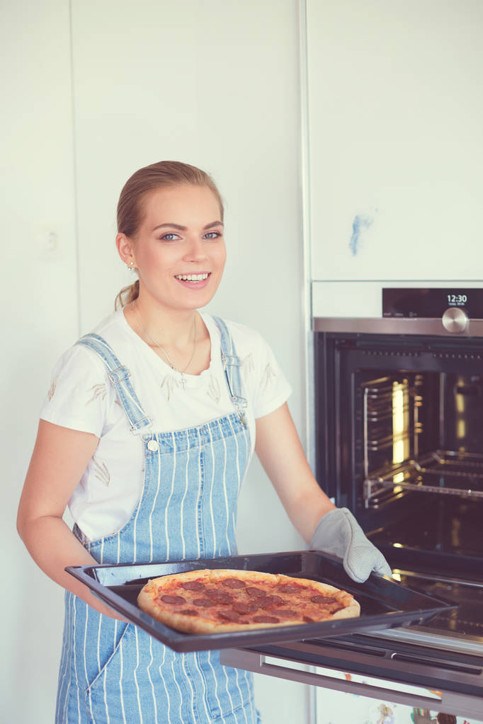 幸せな若い女性クッキングピザ- - 写真・画像