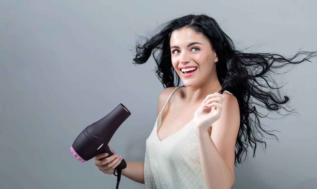 Mulher bonita segurando um secador de cabelo
 - Foto, Imagem