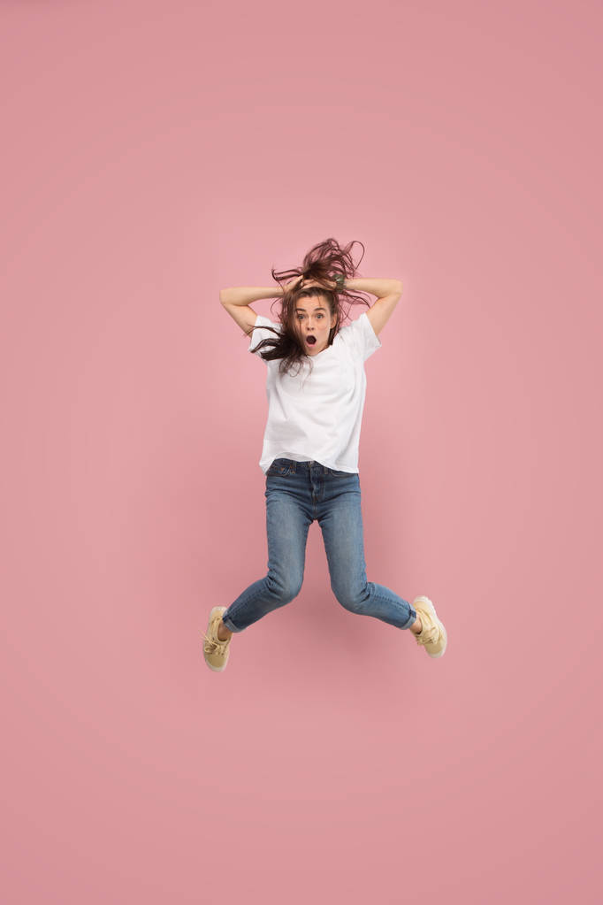 Freiheit in der Bewegung. hübsche junge Frau springt vor rosa Hintergrund - Foto, Bild