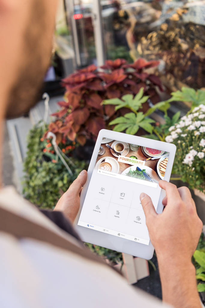 обрезанное изображение флориста с помощью планшета с загруженным квадратным листом возле цветочного магазина
 - Фото, изображение