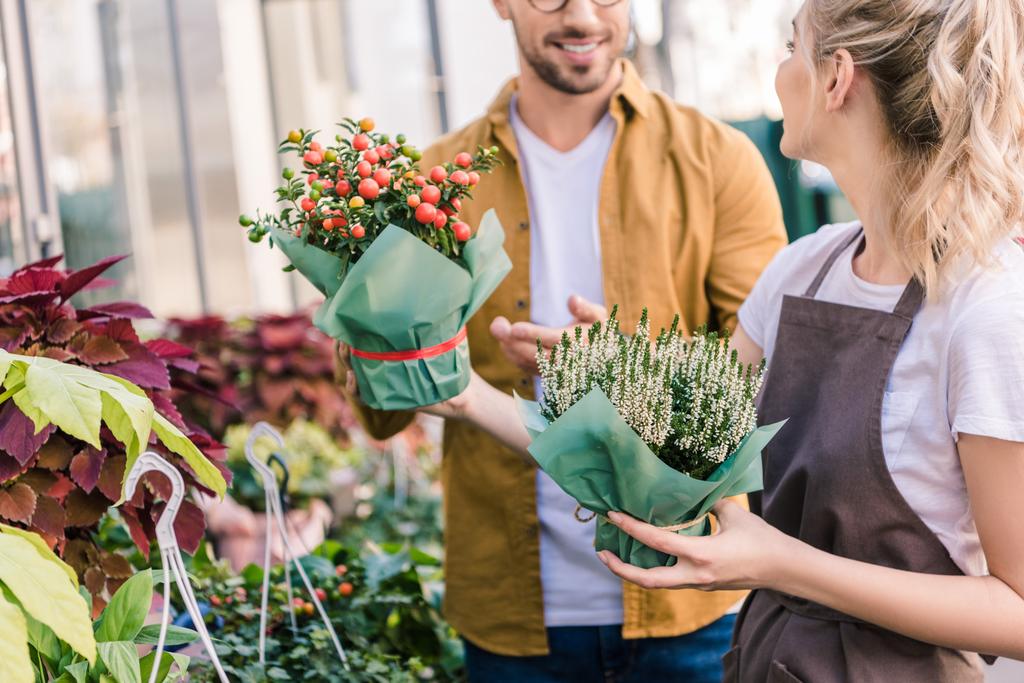 обрезанный образ флориста, помогающего клиенту выбрать цветочный горшок в цветочном магазине
 - Фото, изображение
