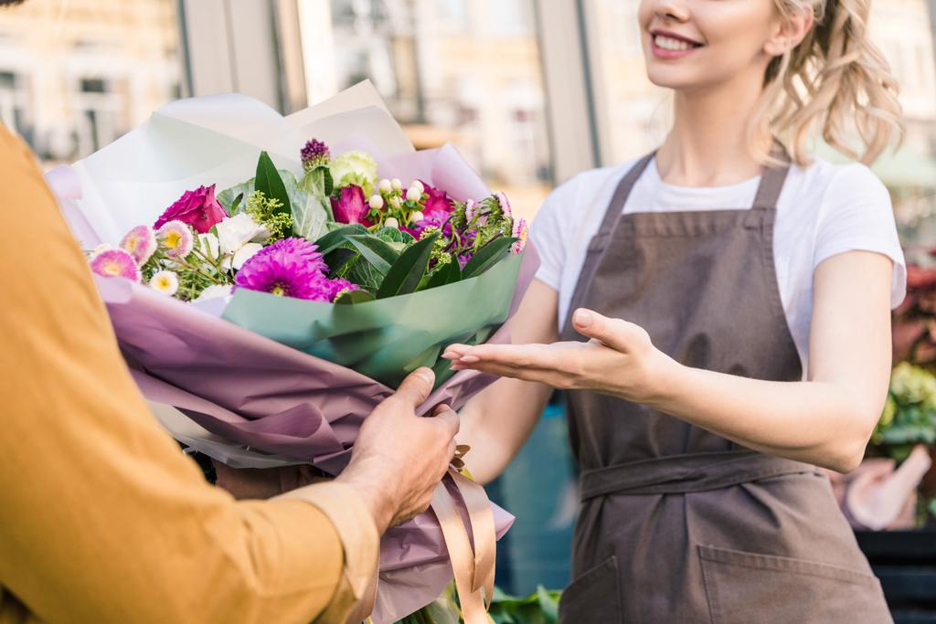 image recadrée de fleuriste donnant beau bouquet de chrysanthèmes au client près de magasin de fleurs
 - Photo, image