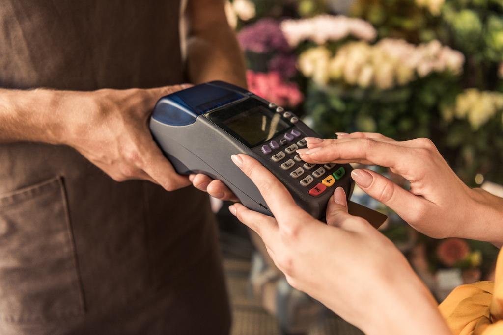 imagen recortada del cliente que paga con tarjeta de crédito en la tienda de flores e ingresando el código del perno
 - Foto, Imagen