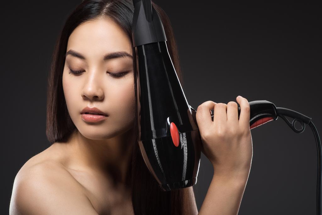 ritratto di donna asiatica con asciugacapelli isolato su nero
 - Foto, immagini