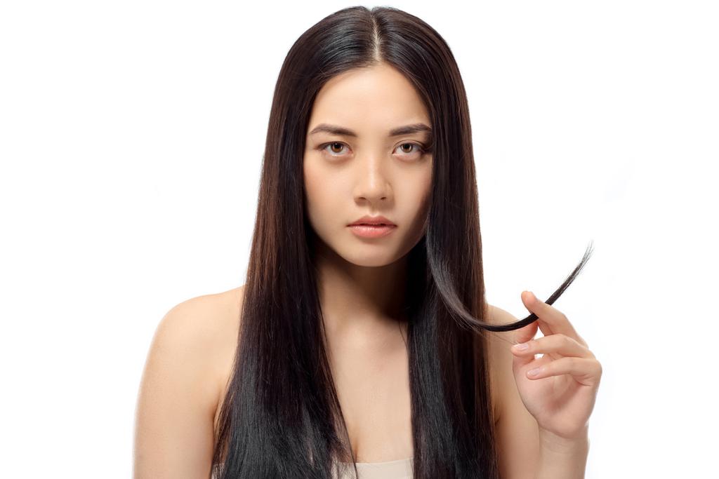 portrait of young asian woman with split ends looking at camera isolated on white, damaged hair concept - Photo, Image