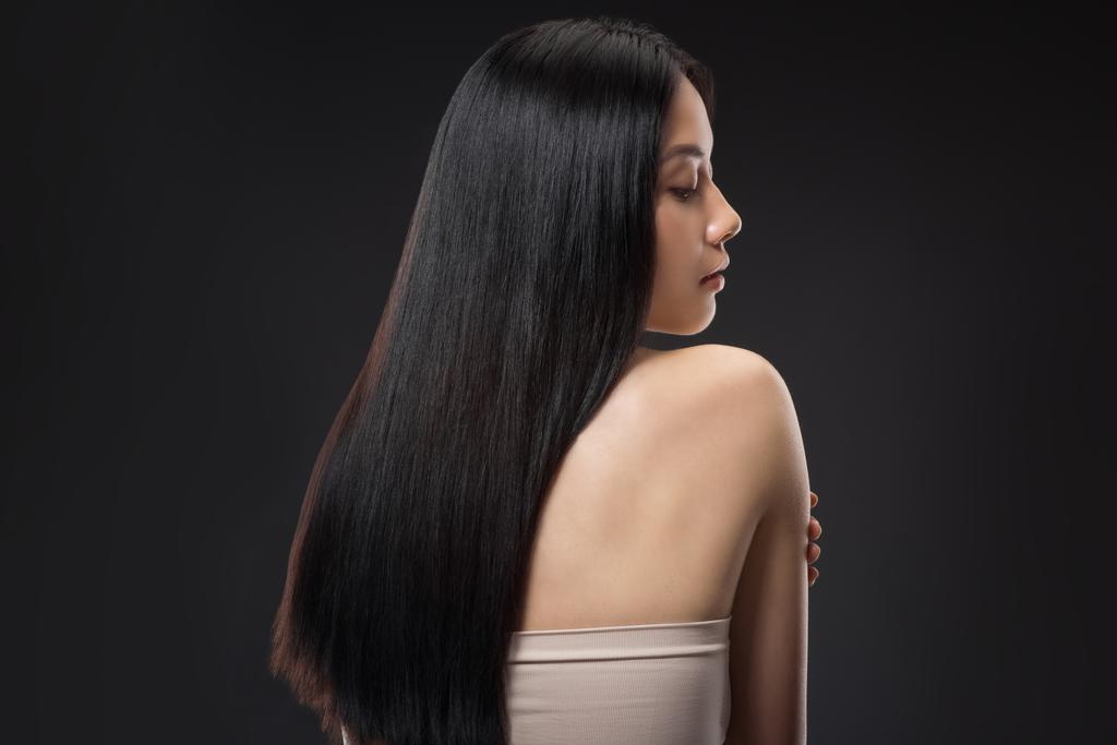 黒に分離されたまっすぐで光沢のある髪の美しいアジアの女性の背面します。 - 写真・画像