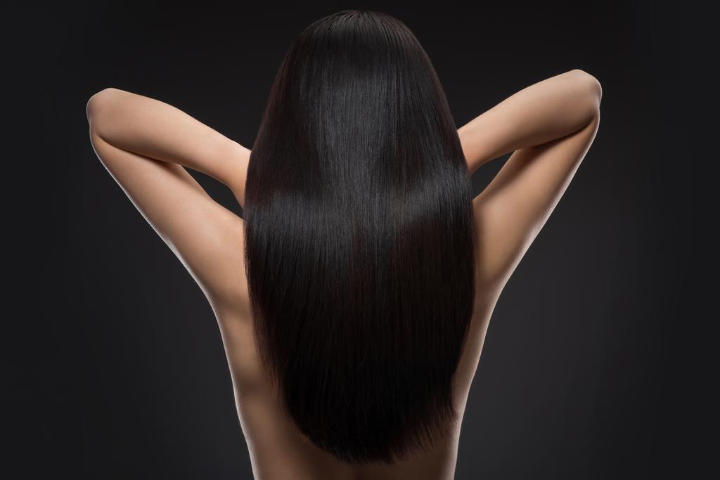 Achteraanzicht van vrouw met mooie glanzende haren geïsoleerd op zwart - Foto, afbeelding
