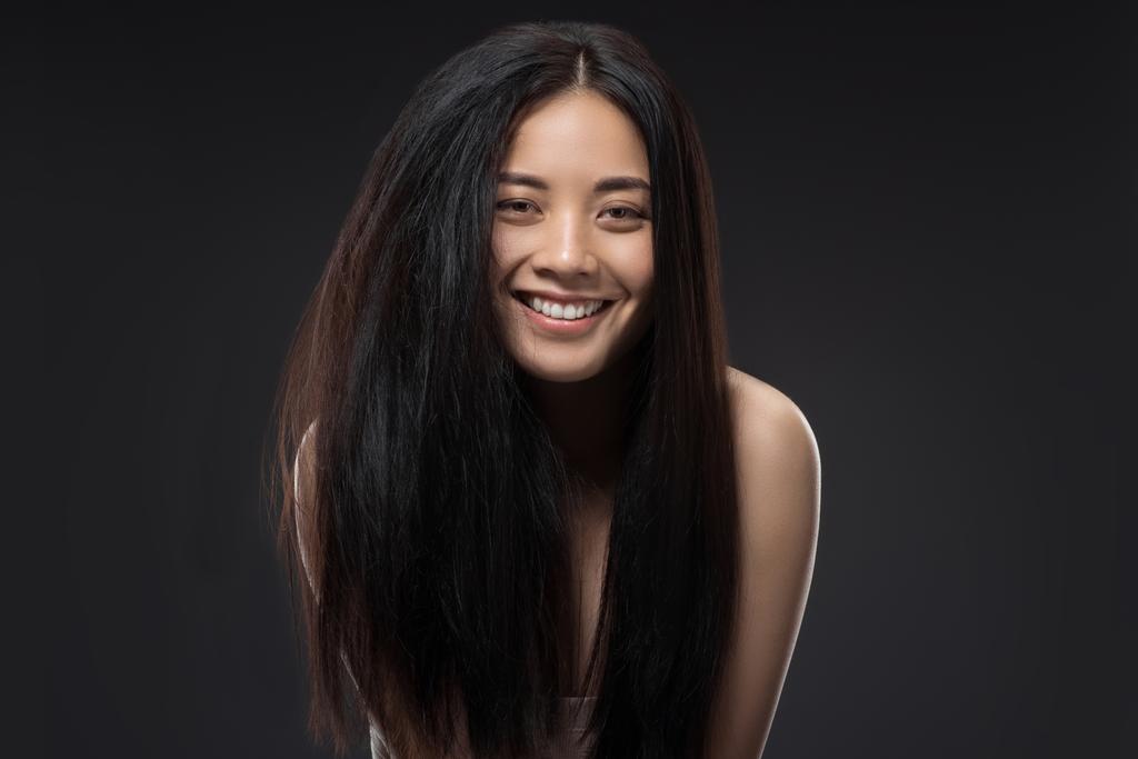 boldog ázsiai nő, szép és egészséges sötét haj látszó-on fényképezőgép, fekete elszigetelt portréja - Fotó, kép