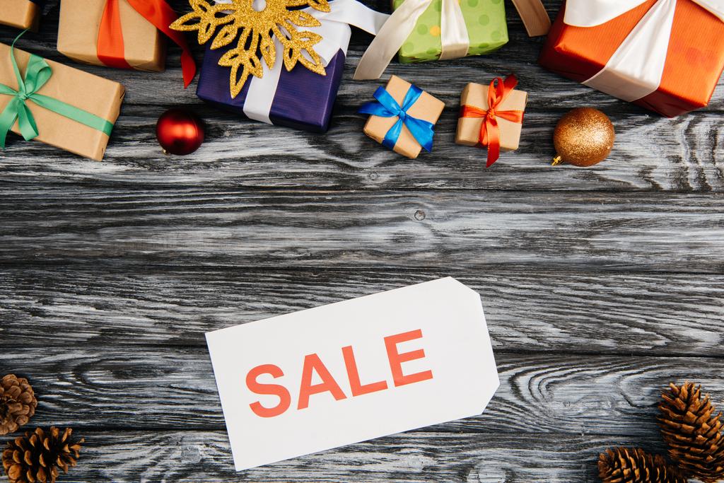 bovenaanzicht van verkoop teken, geschenkdozen en kerstversiering op houten oppervlak - Foto, afbeelding