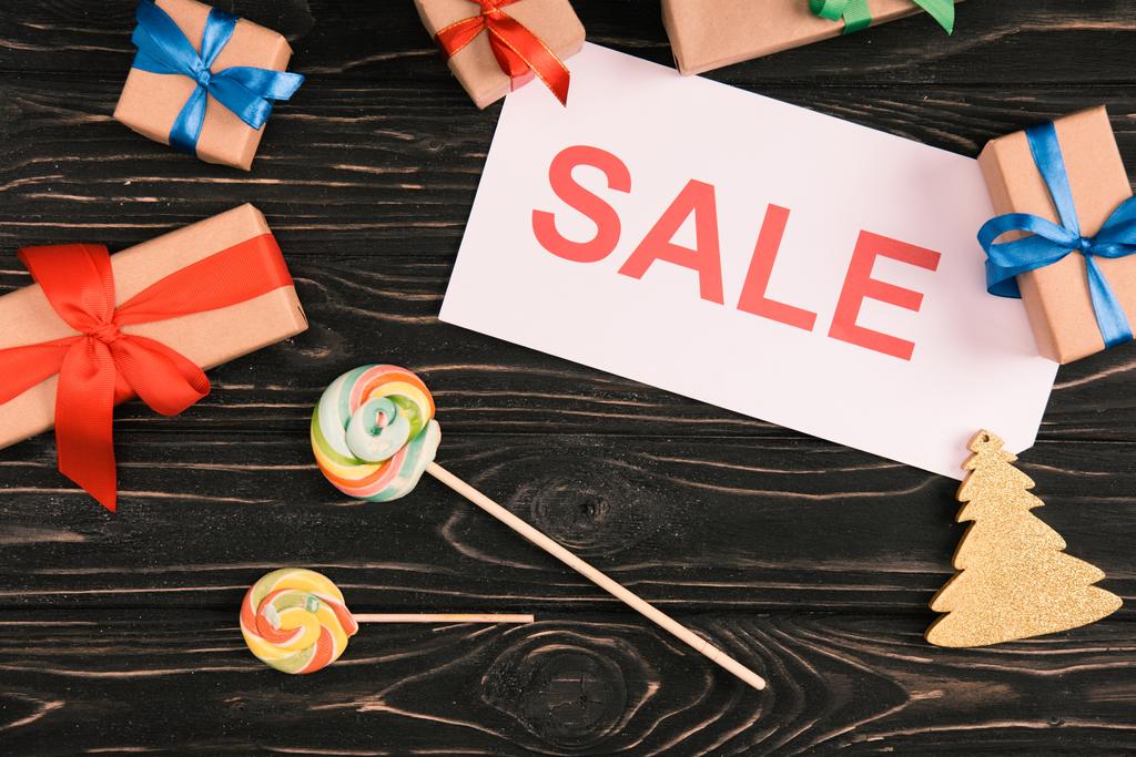 ahşap yüzey üzerinde satışı işareti, lolipop ve Noel hediyeleri üstten görünüm - Fotoğraf, Görsel