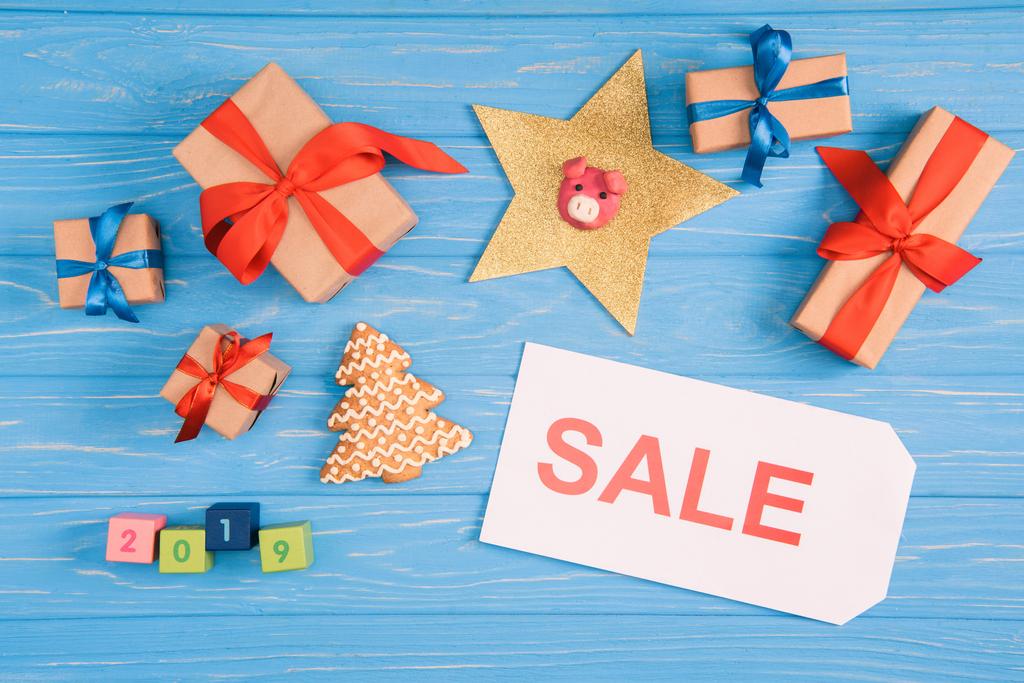 vista superior del cartel de venta, regalos de Navidad y galleta de jengibre en la superficie de madera azul
 - Foto, imagen