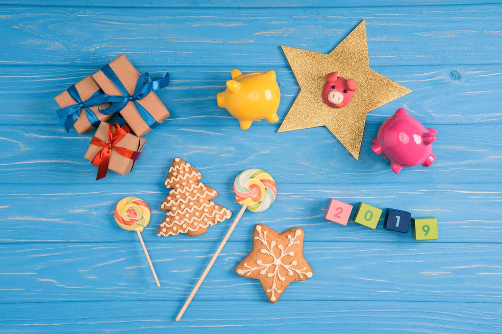 vue du dessus des cadeaux de Noël, bonbons, cochons et 2019 sur cubes sur surface en bois bleu
 - Photo, image
