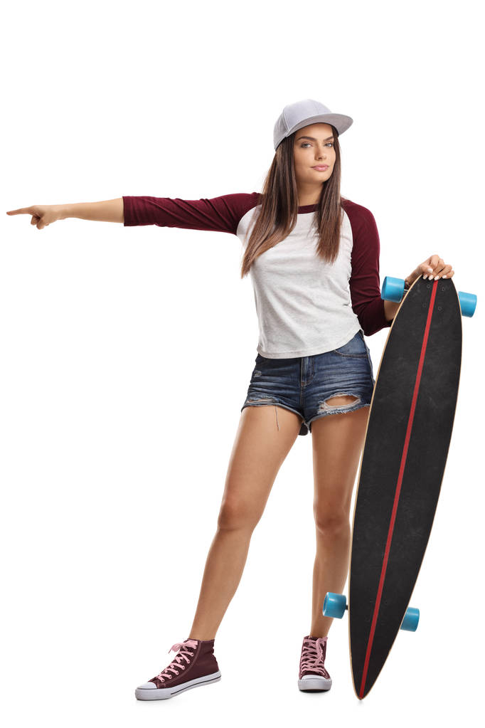 白い背景に分離された 1 つの方向を指すのスケート ボードと若い女性の完全な長さの肖像画 - 写真・画像