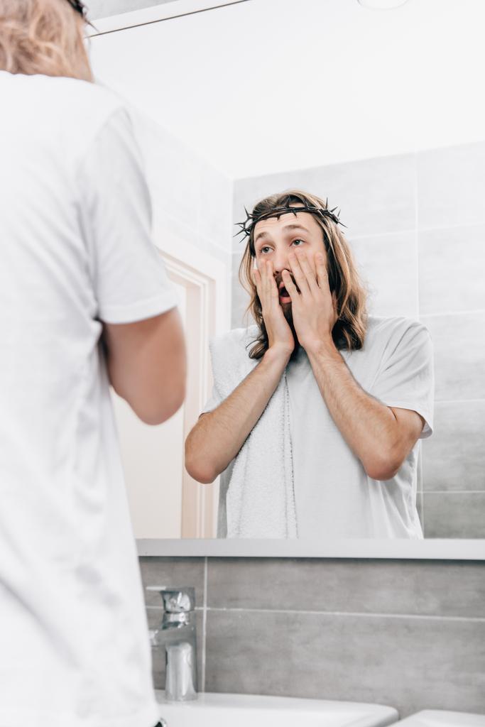 vue arrière de Jésus avec serviette sur l'épaule en regardant son propre reflet dans la salle de bain
  - Photo, image