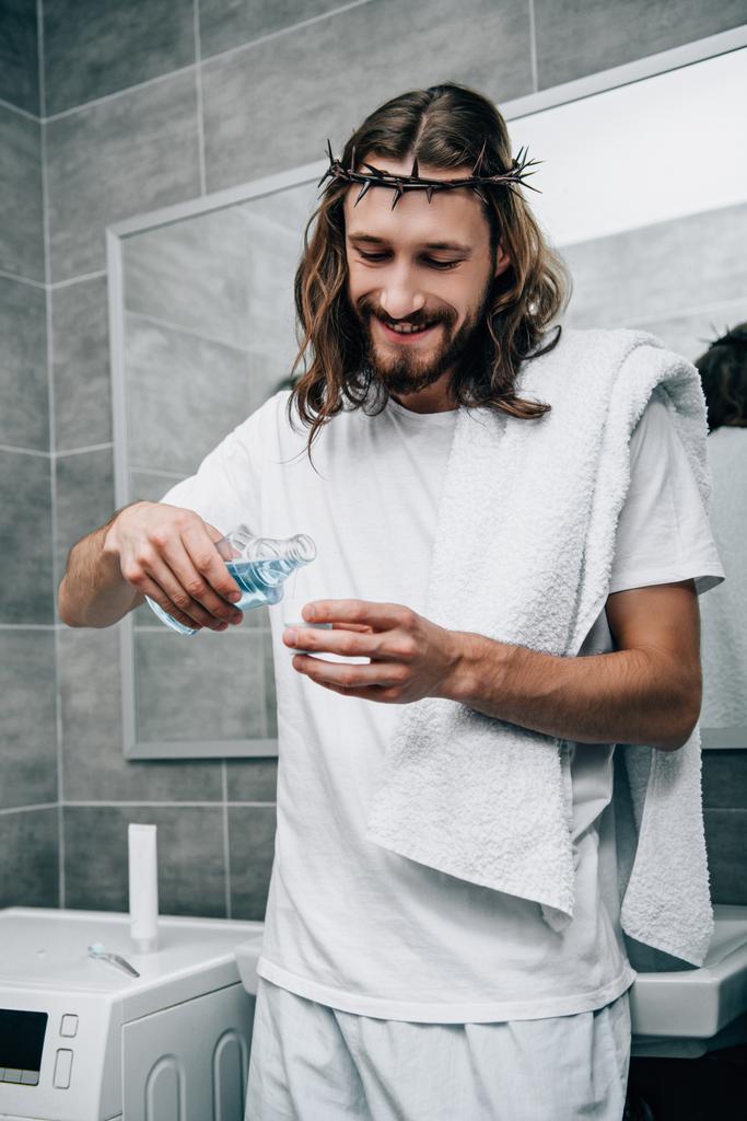 Jesús sonriente en la corona de espinas vertiendo líquido de enjuague bucal en el baño
 - Foto, imagen