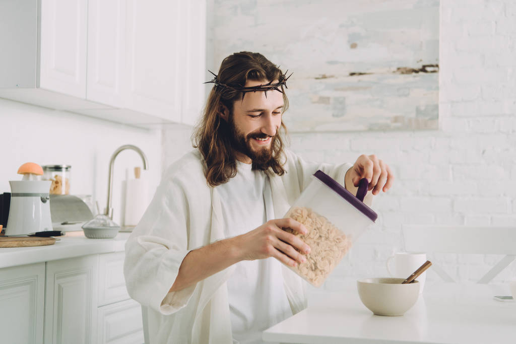 Счастливый Иисус наливает кукурузные хлопья в миску за столом на кухне дома
  - Фото, изображение