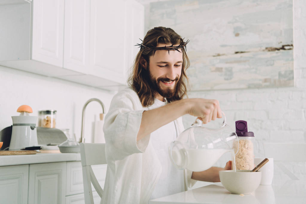 счастливый Иисус наливает молоко в миску с кукурузными хлопьями на завтрак на кухне дома
  - Фото, изображение