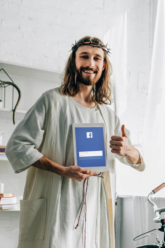 mosolygós Jézus a töviskorona csinál hüvelykujj gesztus és bemutató digitális tabletta-val facebook honlap otthon - Fotó, kép
