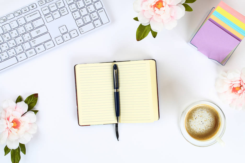 Un blocco note bianco vuoto su un desktop bianco accanto a una tazza di caffè e una tastiera. Vista dall'alto, pianta piatta. Copia lo spazio
 - Foto, immagini