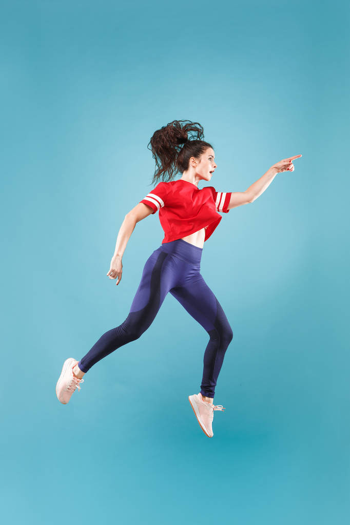 Vrijheid in beweging. Mooie jonge vrouw springen tegen roze achtergrond - Foto, afbeelding