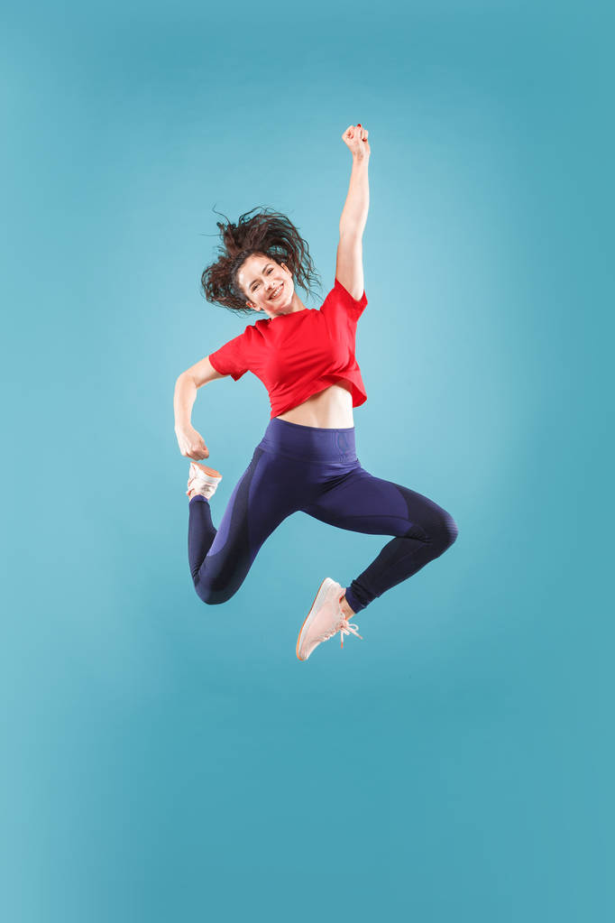 Liikkumisvapaus. Kaunis nuori nainen hyppää pinkkiä taustaa vasten
 - Valokuva, kuva