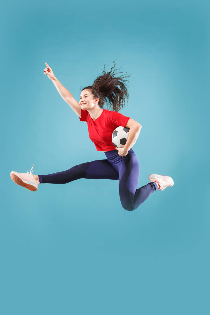 Zafer için ileri. Atlama ve pembe üzerinde stüdyoda topu tekmeleme futbol futbolcu olarak genç kadın - Fotoğraf, Görsel